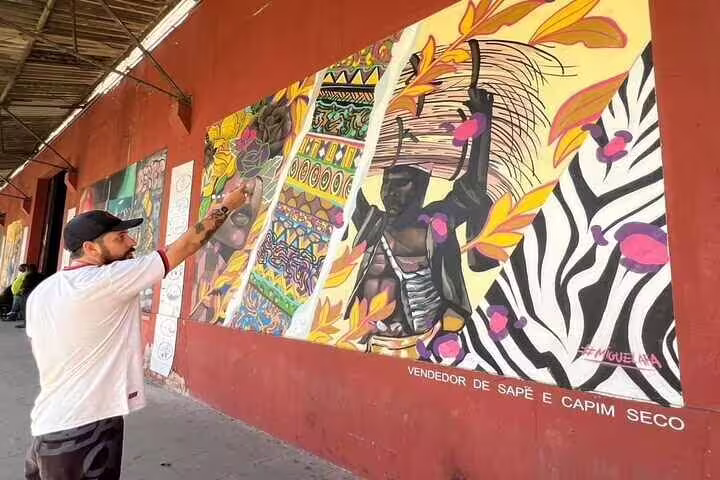 Artist adds details to a colorful mural in Rio, showcasing the dynamic street art scene on the Graffiti Tour.