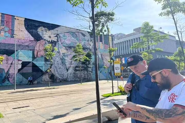 Visitors explore a massive mural in Rio's urban landscape, part of the captivating Graffiti Tour experience.