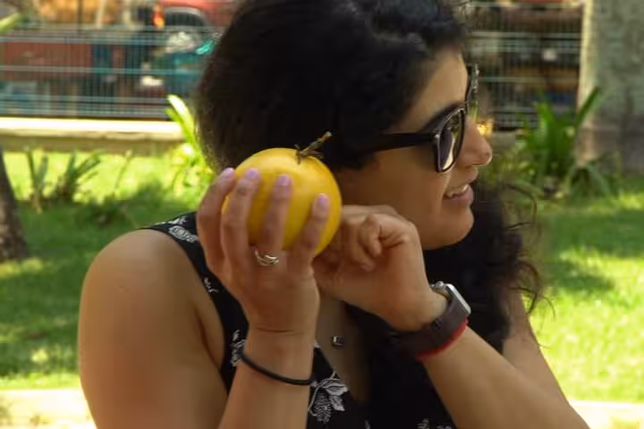 Woman enjoying a tropical fruit during the Rio Tropical Fruit Tour, highlighting vibrant market atmosphere.