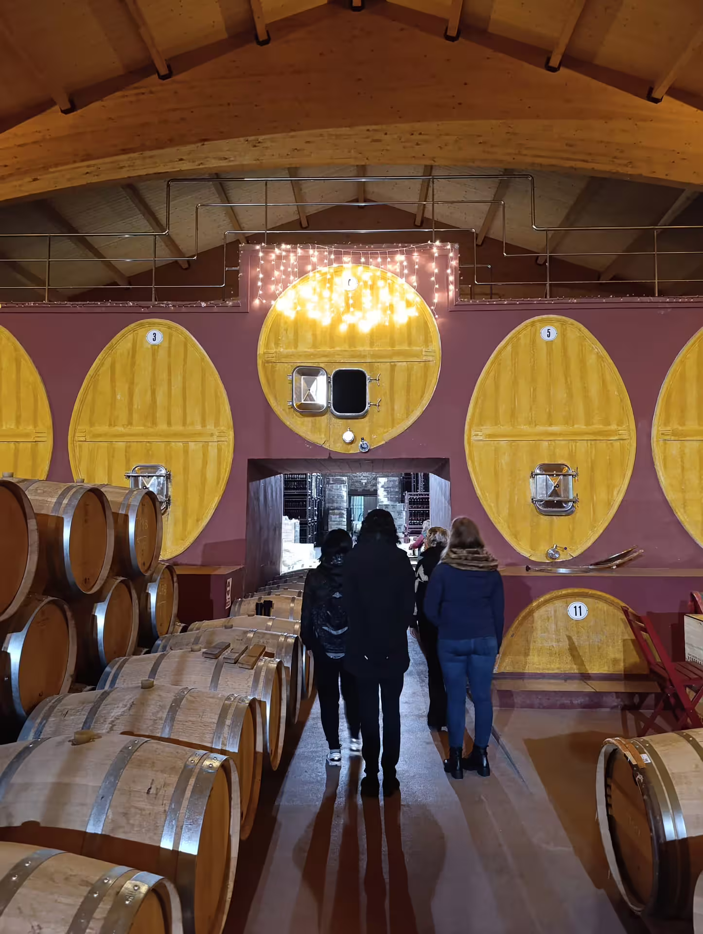 Tourists exploring a Rioja winery cellar with large wooden barrels for an authentic wine experience.