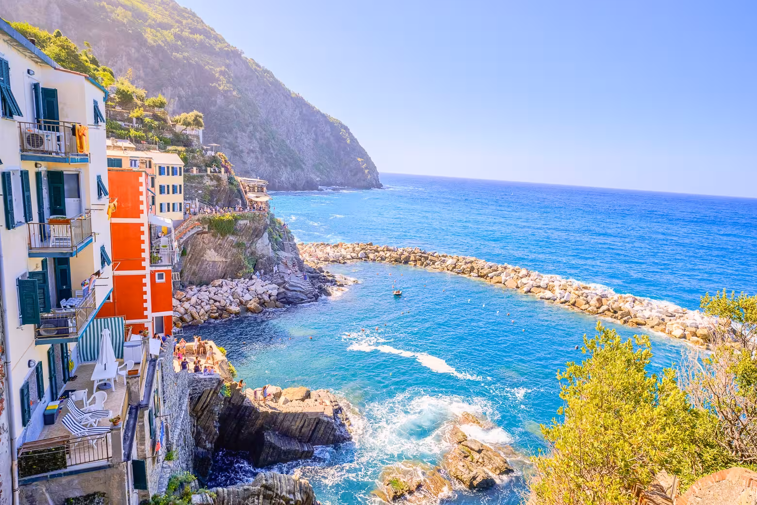 Scenic coastline view of Riomaggiore with vibrant buildings and clear blue sea in Cinque Terre.