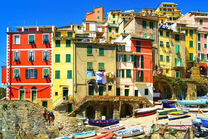 Vibrant Riomaggiore harbor houses and fishing boats on a sunny day, featured on La Spezia to Cinque Terre ship transfer tour