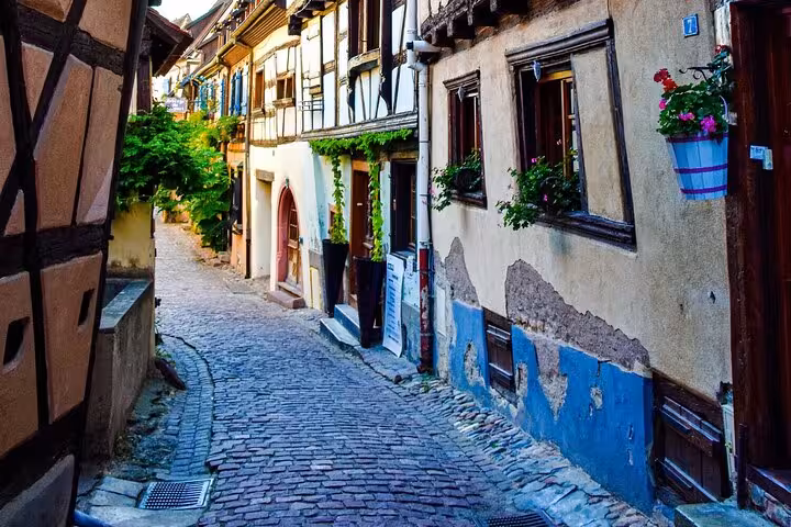 Cobblestone alley with half-timbered houses and flower boxes in Riquewihr, Alsace, France