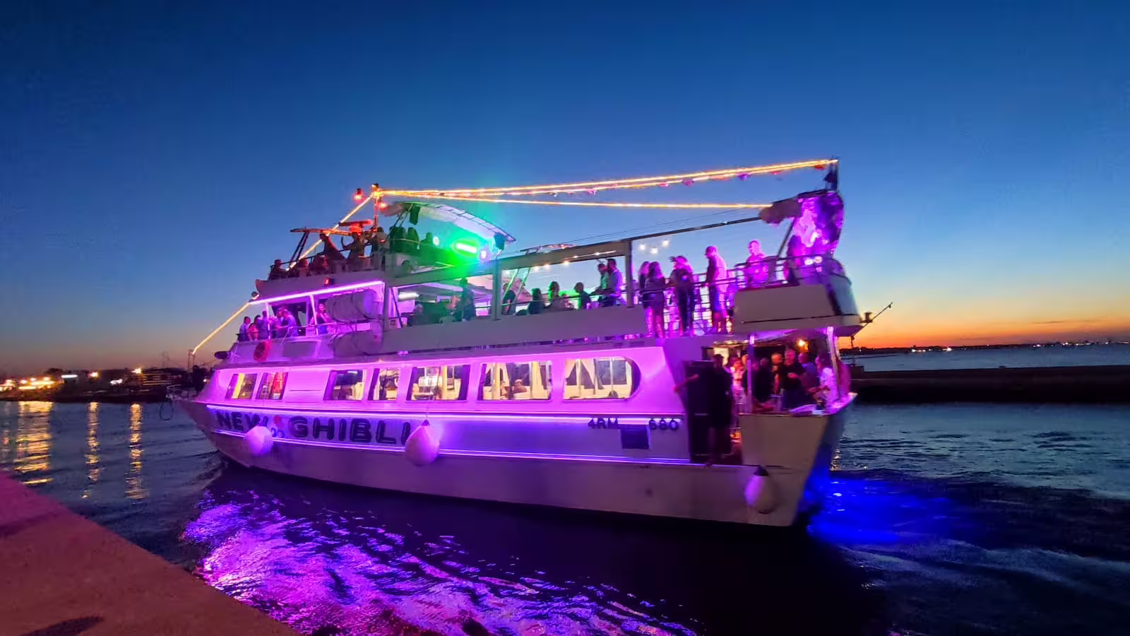 Sunset party boat with colorful lights departing on a Riviera Romagnola half-day cruise from the Adriatic harbor