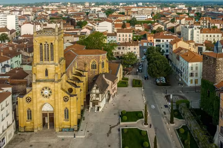 Aerial view of Roanne's Gothic church and town square surrounded by terracotta-roofed buildings