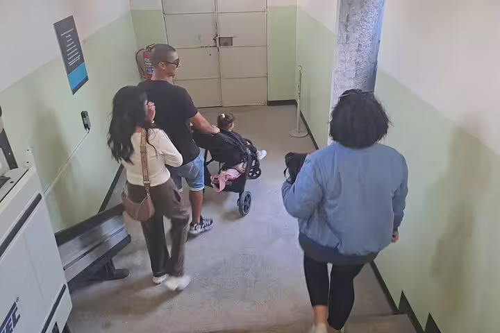 Family with a stroller descends stairs on Robben Island tour, offering an accessible and educational museum experience.