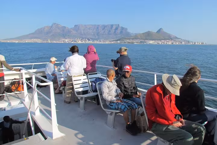 Tourists enjoy a scenic ferry ride to Robben Island with Cape Town's Table Mountain in the background.