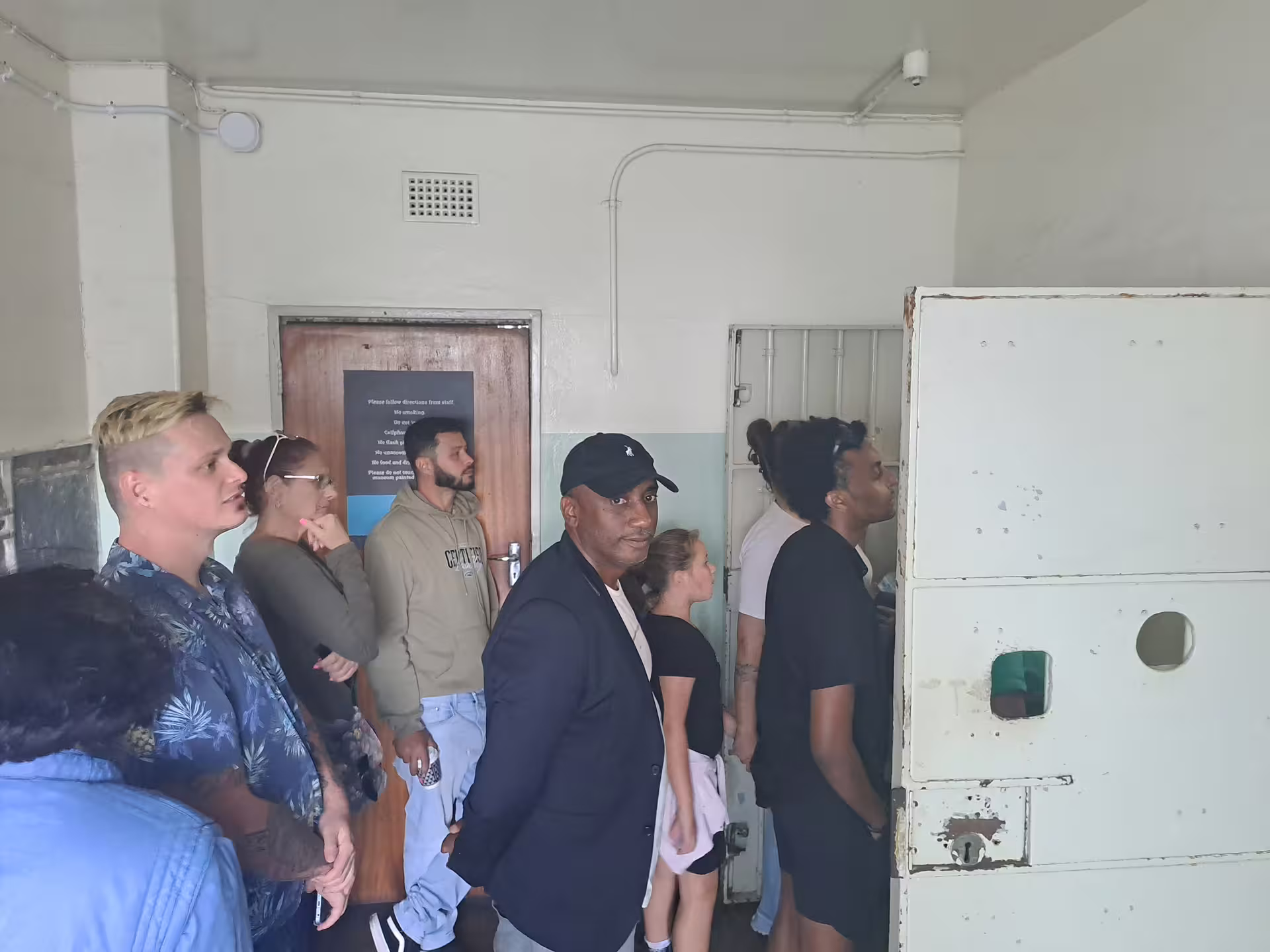 Tourists exploring a historic cell at Robben Island Museum during a ferry tour with convenient hotel transfer.