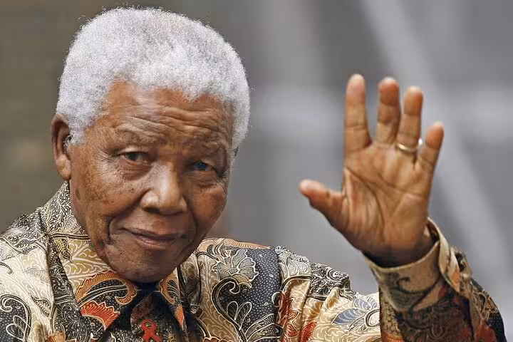 A person waving with a warm smile, symbolizing the historical significance of Robben Island in South African history.