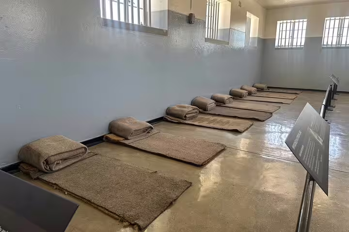 Interior of a Robben Island prison cell with basic bedding, showcasing historical significance on the half-day tour.