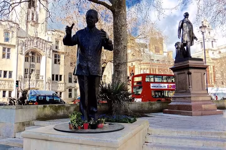 Statues near a red double-decker bus and historic buildings, signifying cultural and historical tours in Cape Town.