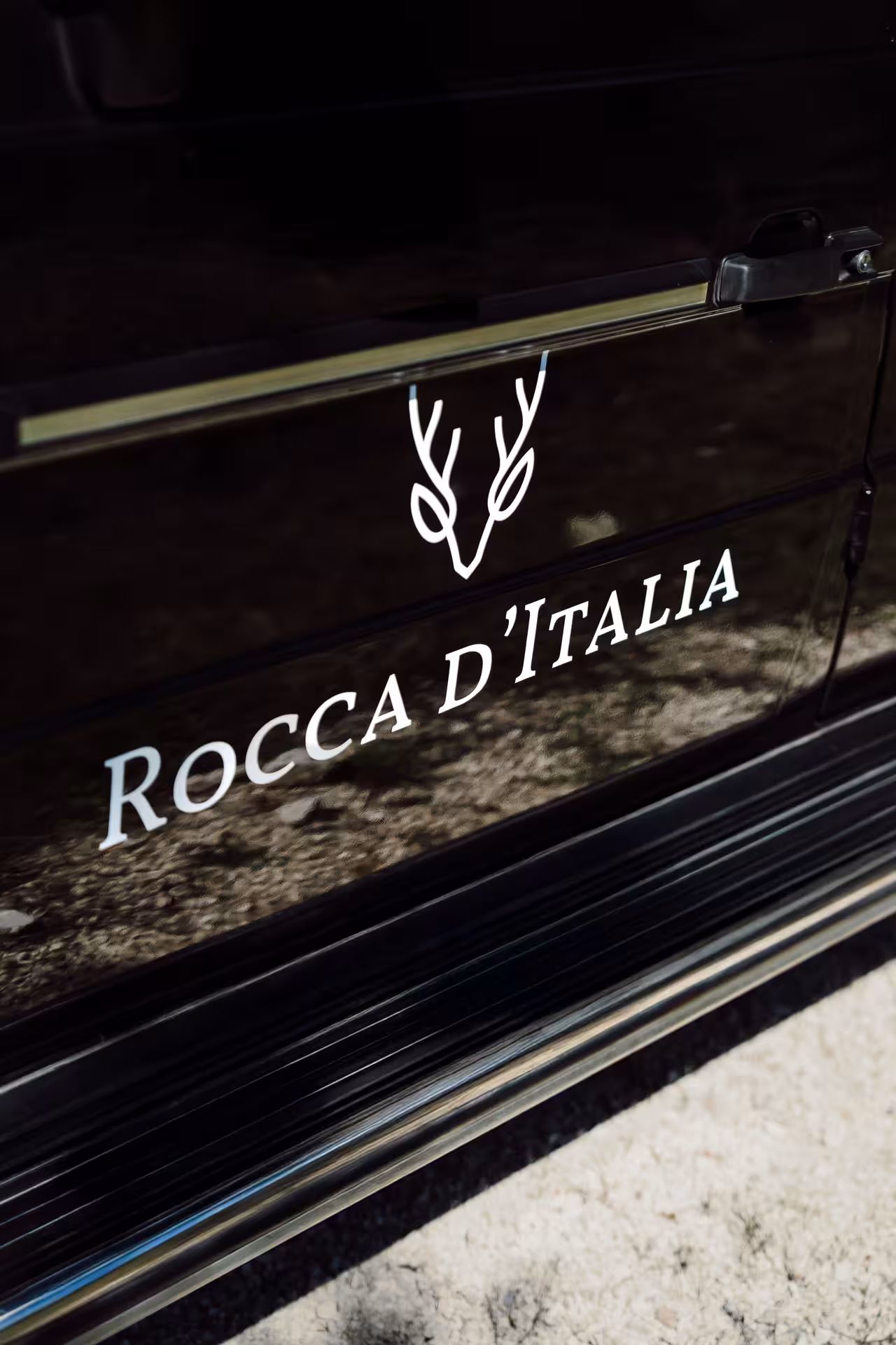 Rocca d'Italia branded black car door with white antler logo for Tuscany wine tour