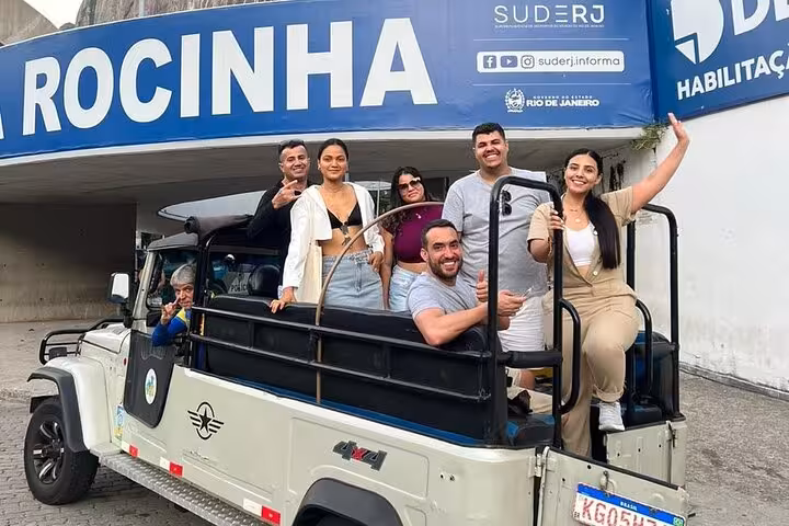 Tourists in an open jeep under a Rocinha sign, exploring the largest favela in Latin America with a local guide.