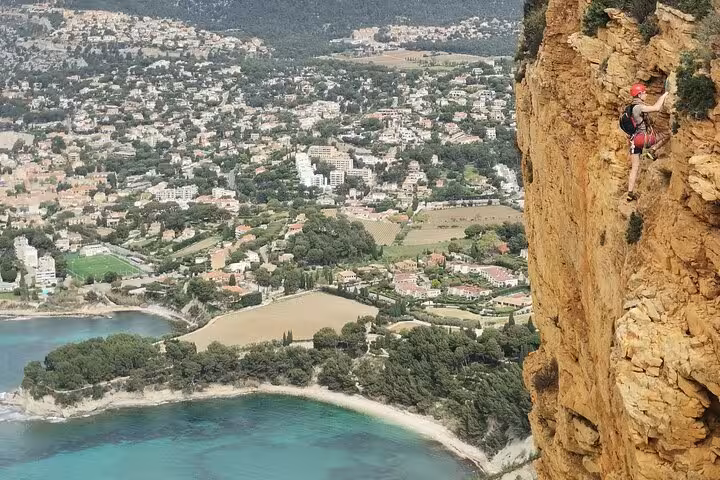 Rock climber above turquoise lake and valley views in Provence, reached on a private driver day trip