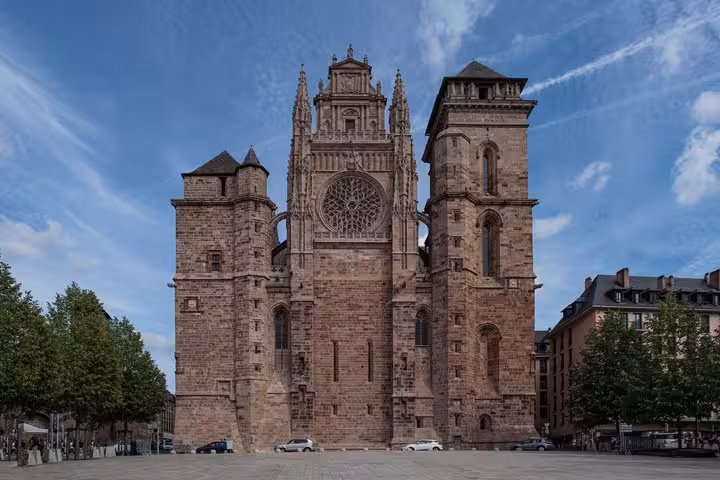 Gothic facade of Rodez Cathedral Saint-Etienne with rose window and stone towers under blue sky