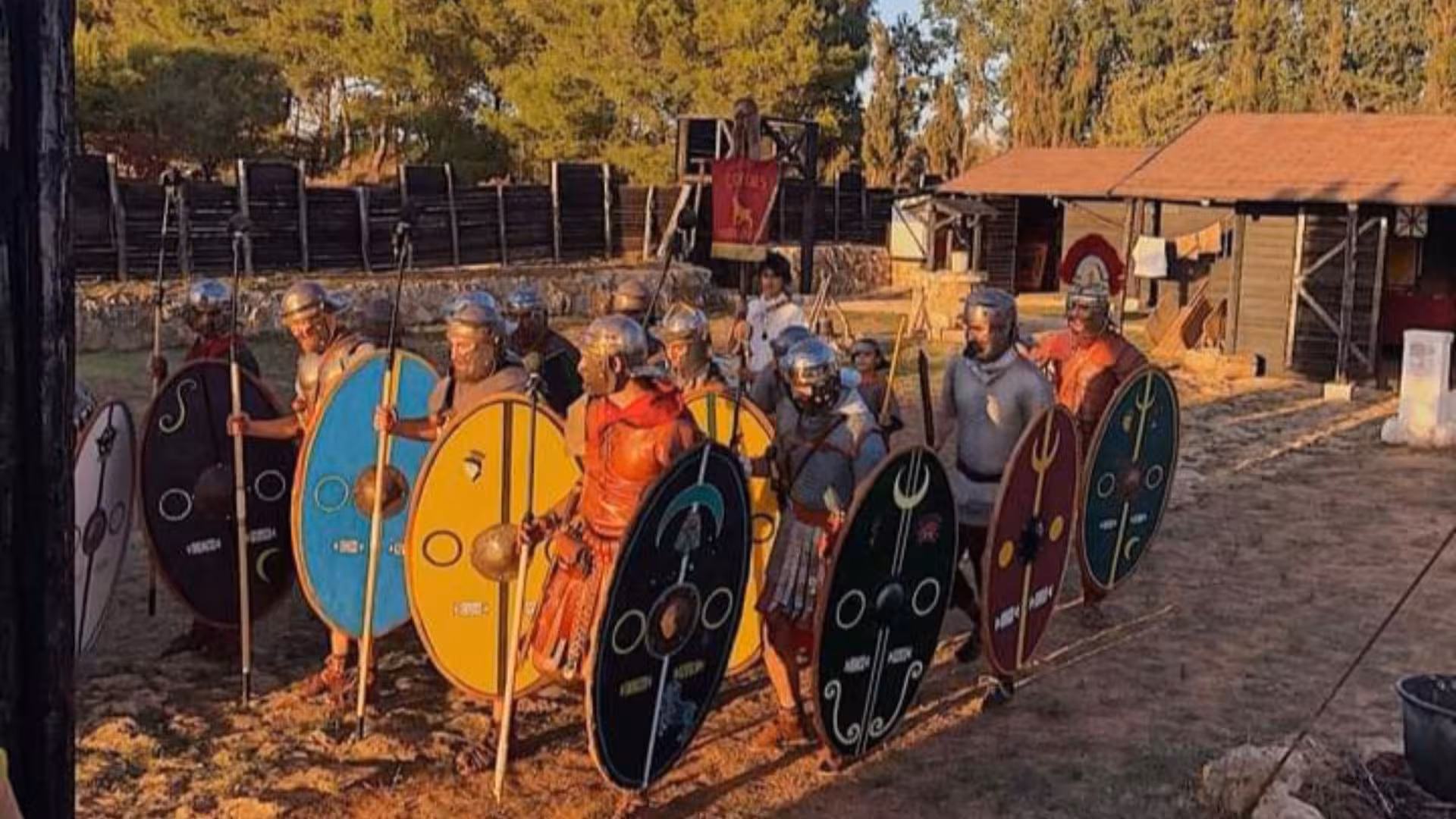 Group of reenactors in Roman armor with shields at Sassari's Roman Castrum during an educational tour.