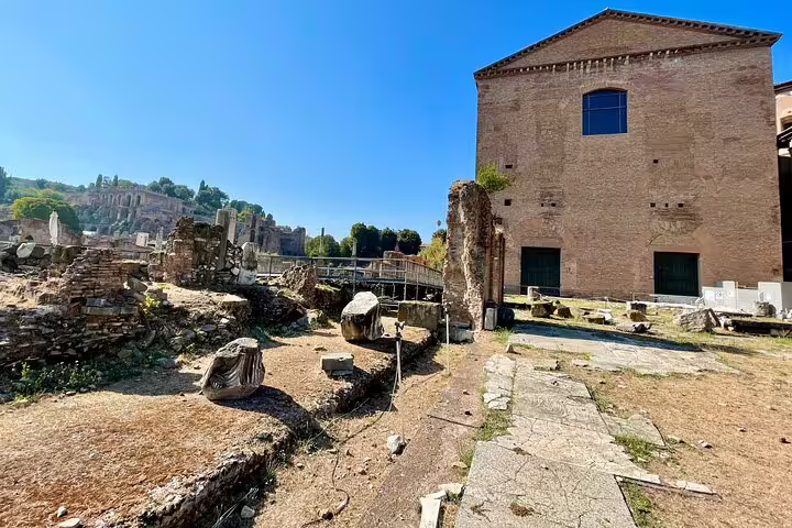 Sunlit ruins and brick halls of the Roman Forum with scattered marble fragments seen on a Rome Colosseum walking tour