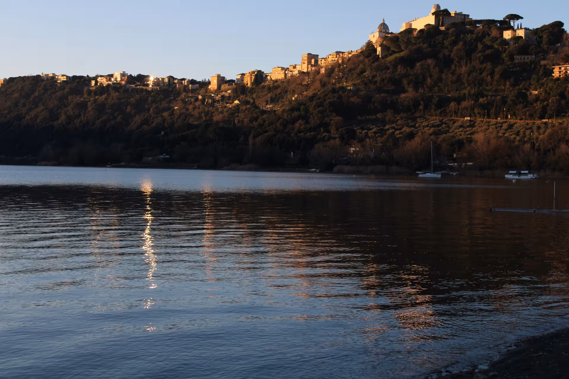 Scenic view of Roman hills and shimmering lake at sunset, ideal backdrop for a Fiat 500 vintage tour.
