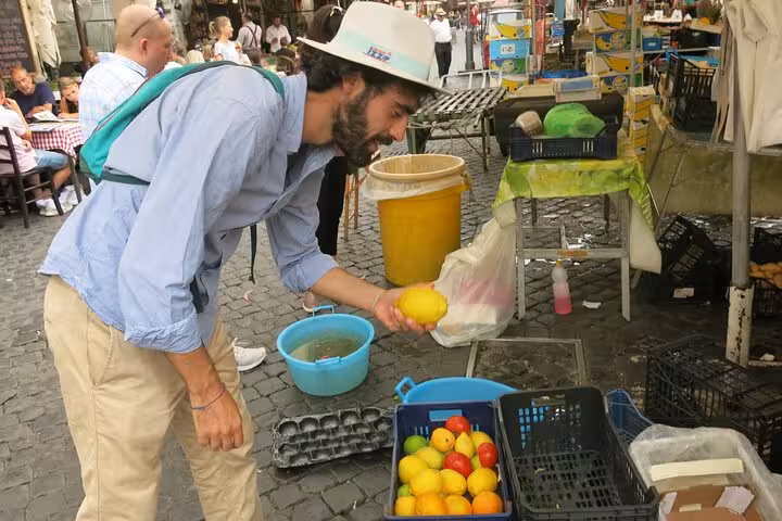 Man selecting fresh lemons at a bustling Roman market during a private vegetarian food tour.