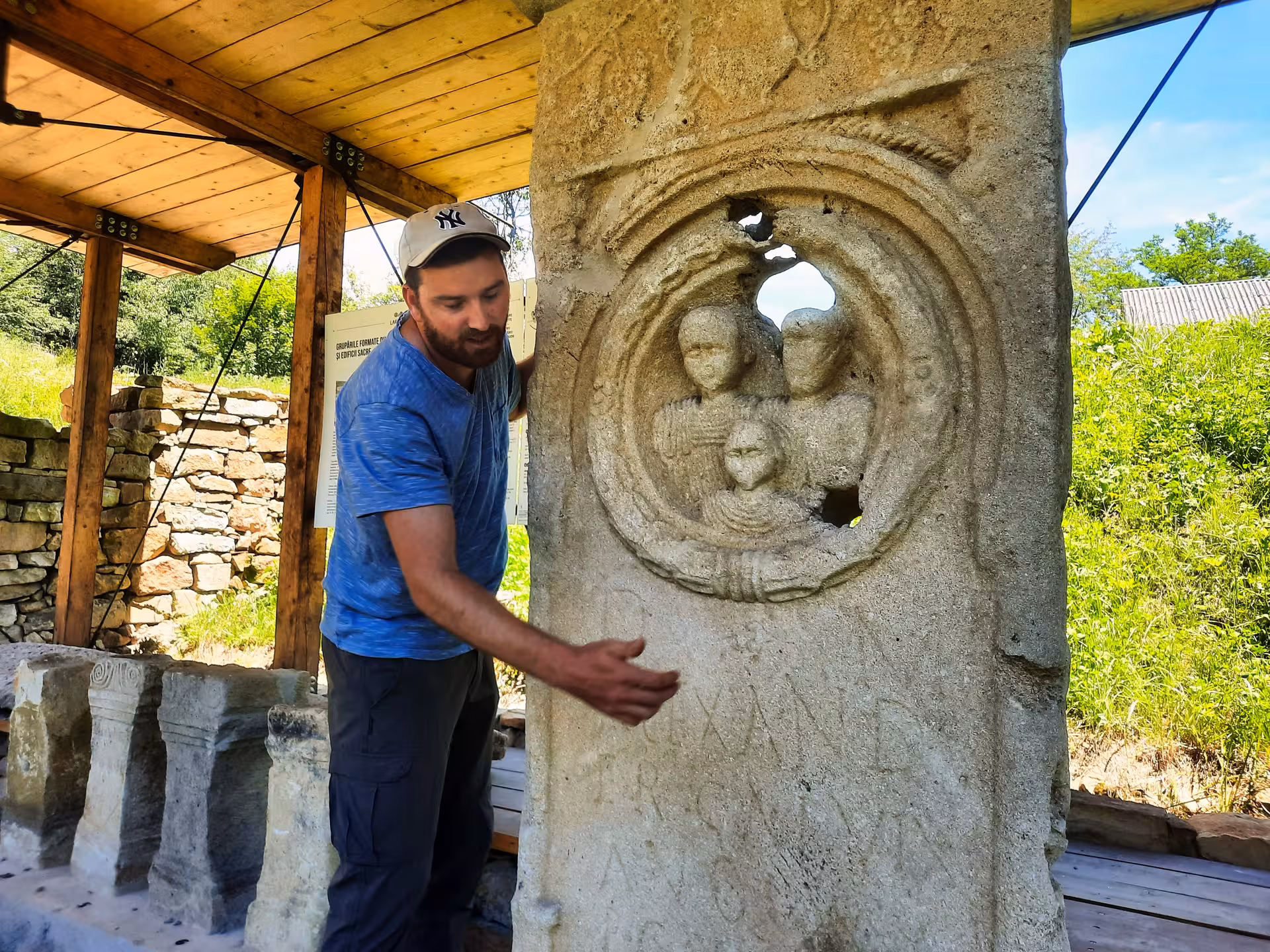Guide examining ancient Roman funerary stele with carved relief at Rosia Montana archaeological site