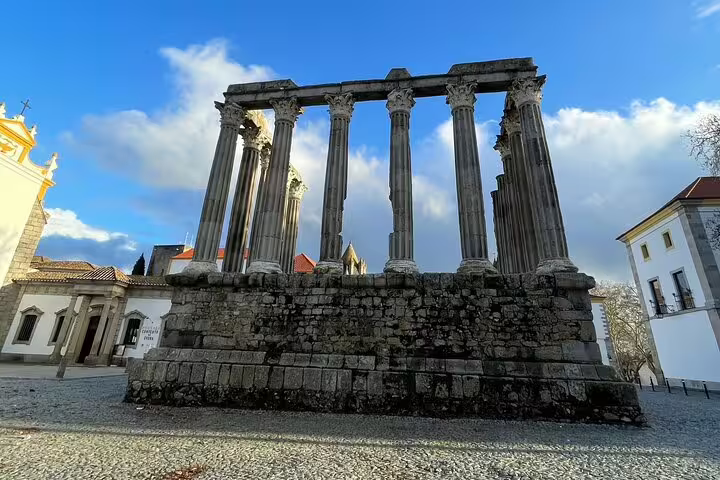 Ancient Roman Temple of Évora under a blue sky, featuring well-preserved columns and historic stonework.