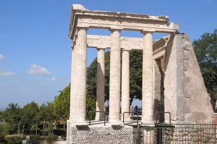 Ancient Roman temple ruins bask in sunlight, offering a glimpse into history on the Wine Tour South of Rome.