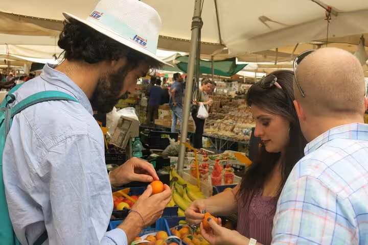 Participants examining fresh apricots at a bustling Roman market on the Private Roman Vegetarian Food Tour.