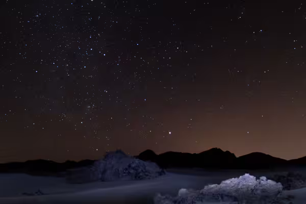 Starry night sky over snowy landscape and mountains in Romania for stargazing tour