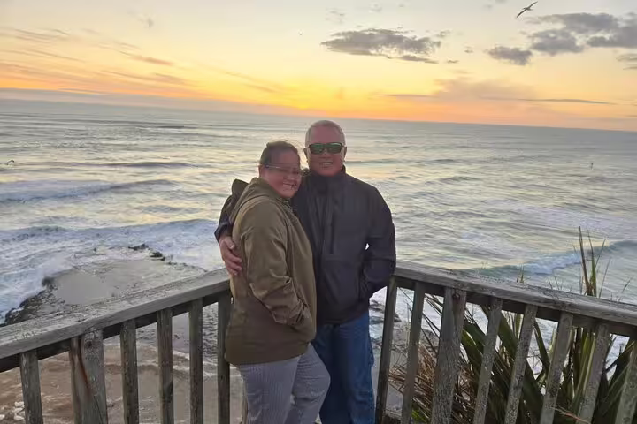 Couple enjoying a romantic Auckland sunset on a coastal lookout, perfect for a sunset tour with winery and thermal pool.
