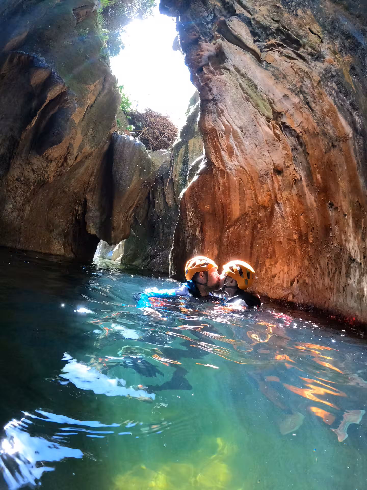 Couple sharing a romantic kiss while swimming in crystal-clear turquoise water during a canyoning adventure in Guadalmina Canyon Estepona