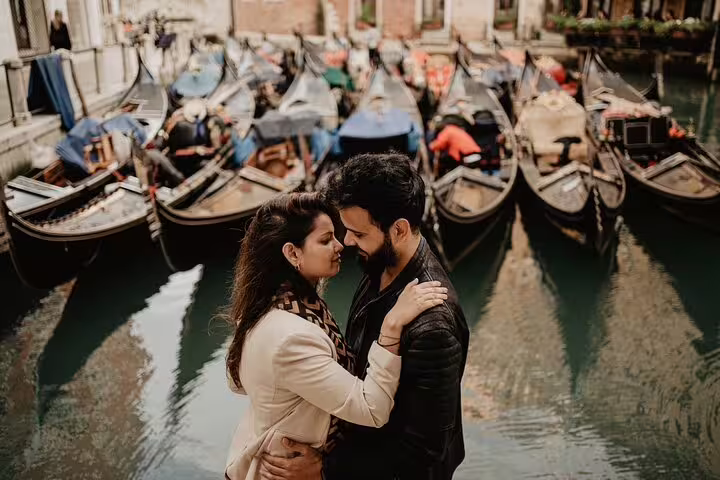 Romantic couple photo shoot by Venetian gondolas during private gondola ride with pro photographer