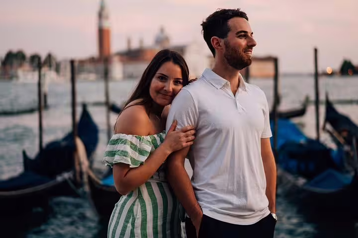 Romantic couple by gondolas at sunset in Venice, captured by proposal photographer for surprise engagement