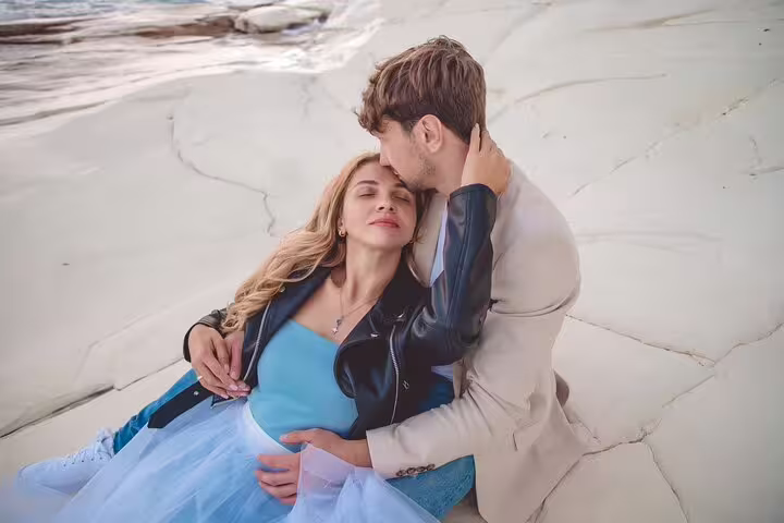 Romantic couple embracing on a sunlit rock formation during a private photoshoot in Ayia Napa.