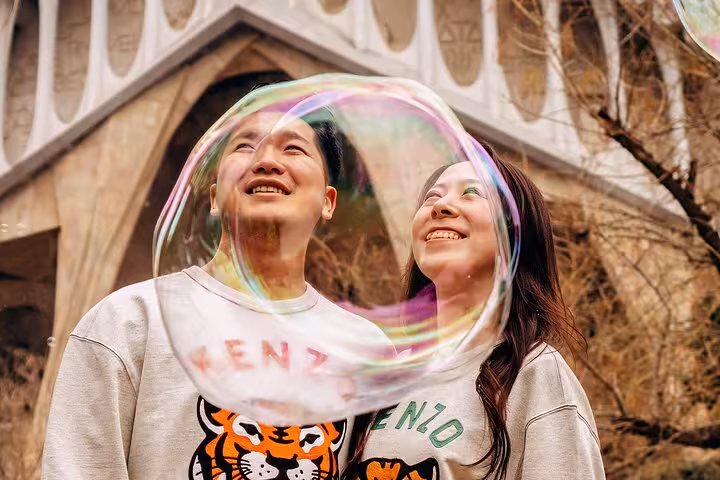 Romantic couple photoshoot at Sagrada Família, Barcelona, with playful soap bubbles and Gaudí architecture in the backdrop.