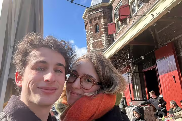 Couple taking a selfie at an Amsterdam outdoor café with historic brick building in background
