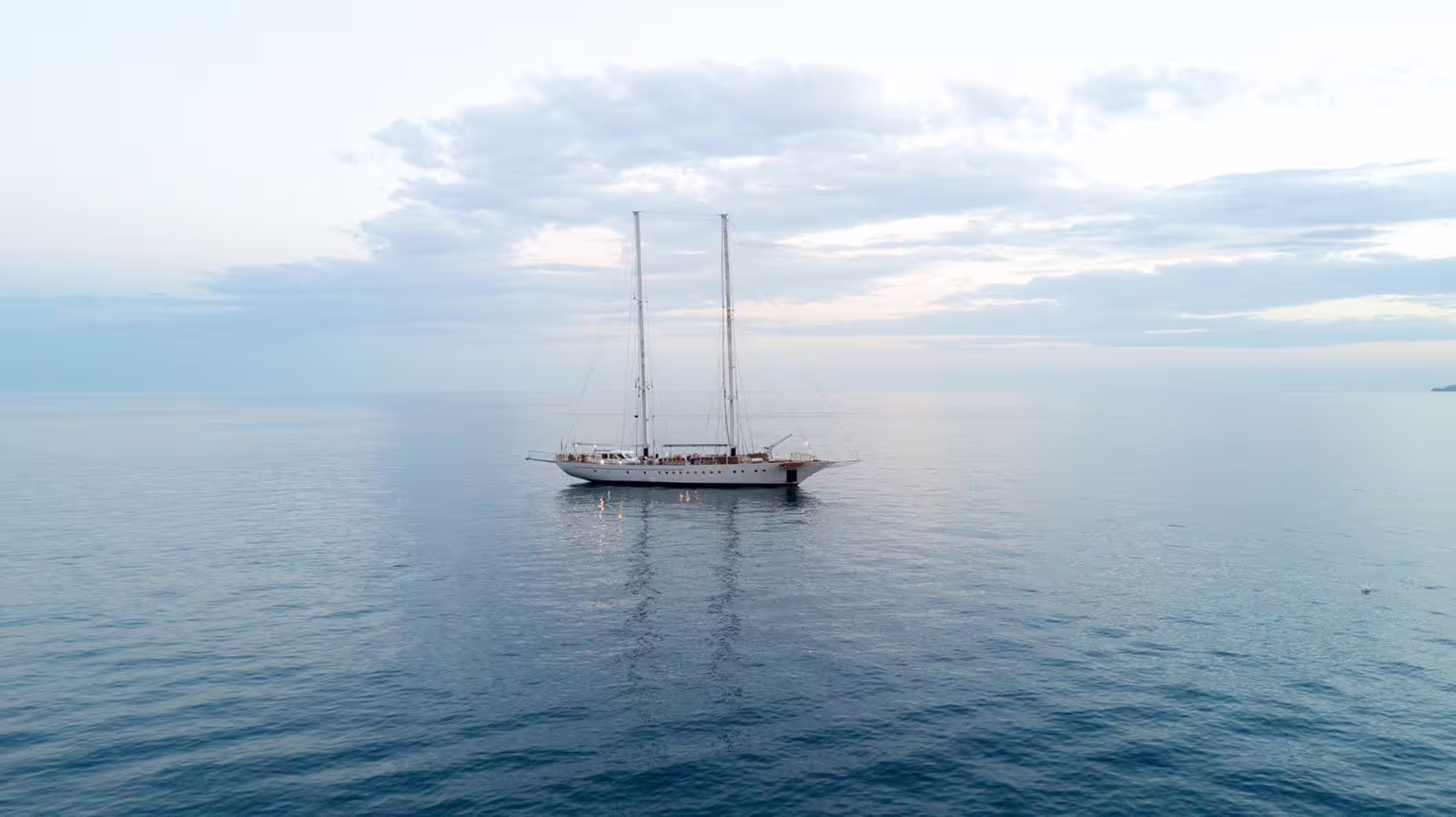 Elegant sailing ship anchored at sunset in the calm Gulf of Naples, hosting a romantic dinner show cruise experience