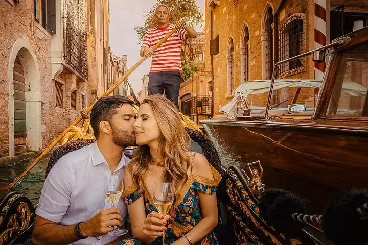 Couple enjoys a romantic gondola ride in Venice, sipping champagne and sharing a kiss under the warm Italian sun.