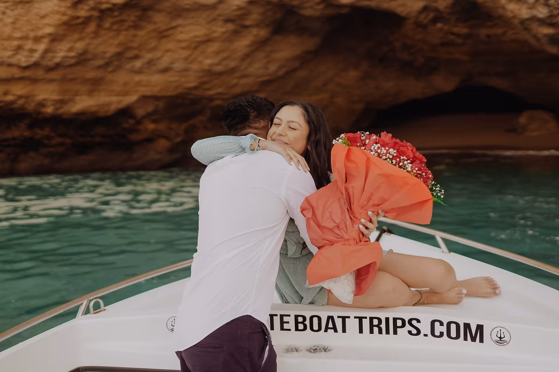 Romantic proposal on a private Benagil Caves boat tour, woman holding bouquet against turquoise Algarve waters