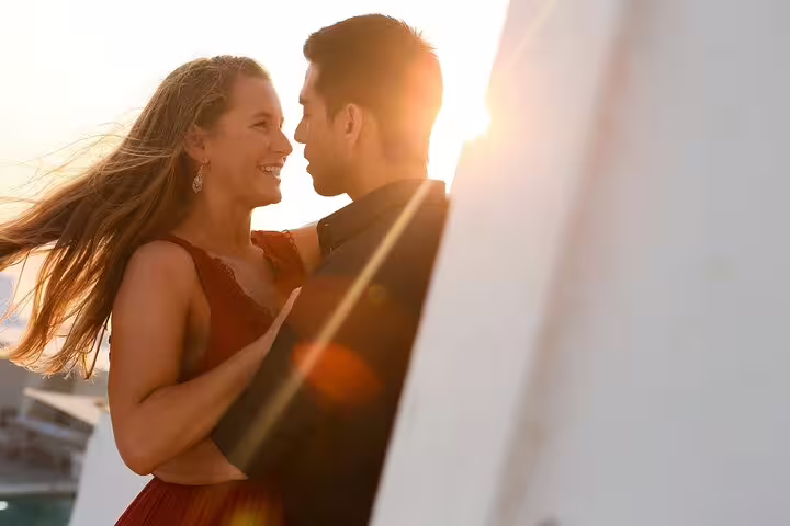Romantic Santorini proposal photo at sunset, couple embracing on white terrace with golden light
