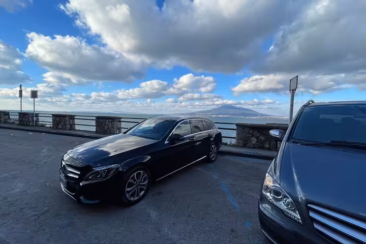 Scenic view with luxury sedan overlooking the Amalfi Coast, ideal for private transfer from Rome.