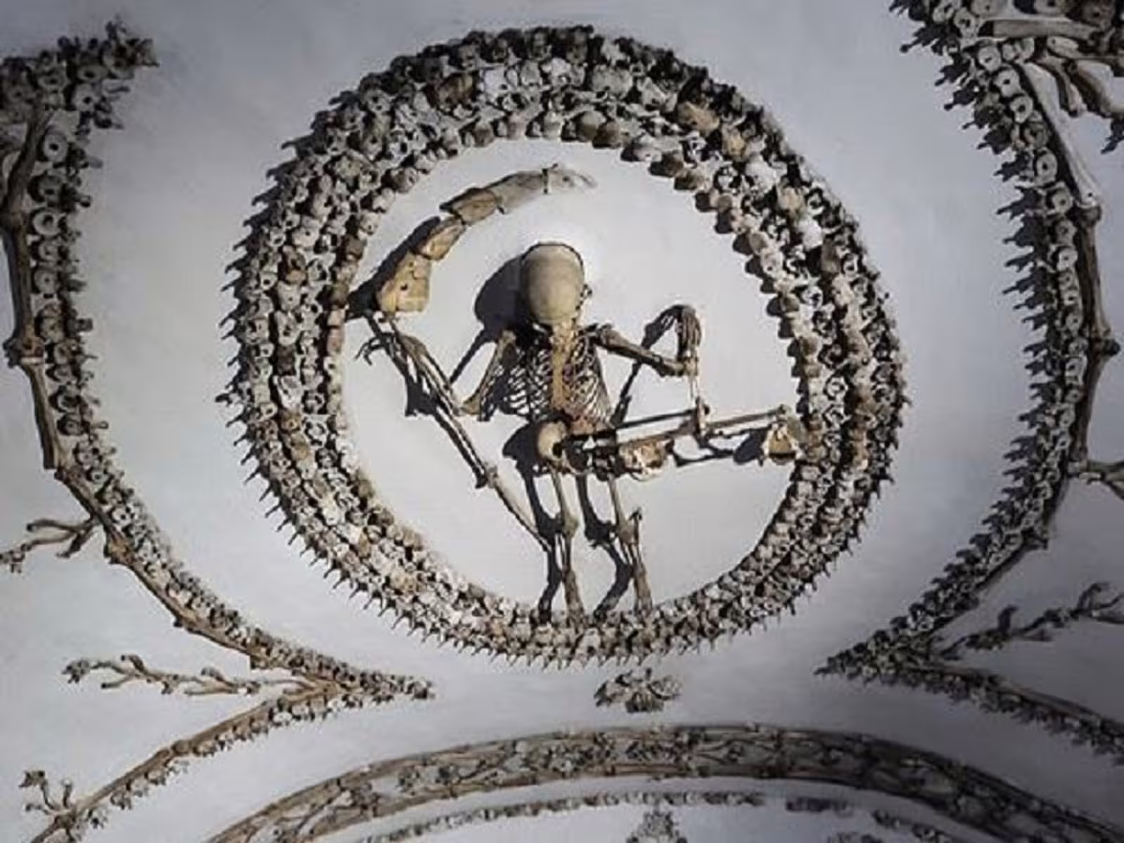 Skeleton artwork forming a grim reaper on a vaulted ceiling in Rome’s Capuchin Crypt, visited on underground catacombs tours