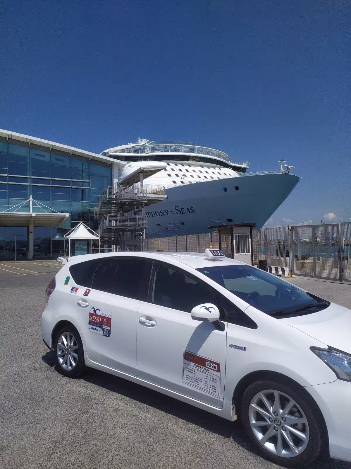White taxi parked near a cruise ship at Civitavecchia port, offering transfers to and from Rome city center.