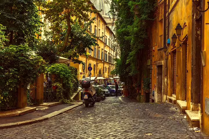Charming cobblestone street in Rome, lined with historic buildings and lush greenery, ideal for a private walking tour exploration.