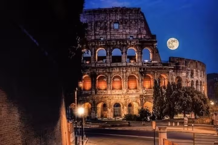 The Colosseum beautifully lit under a full moon on an evening golf cart tour in Rome with complimentary pick-up.