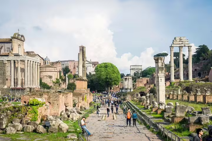 Visitors walk among ancient columns and ruins in the Roman Forum on a Rome Private VIP Colosseum and Vatican tour