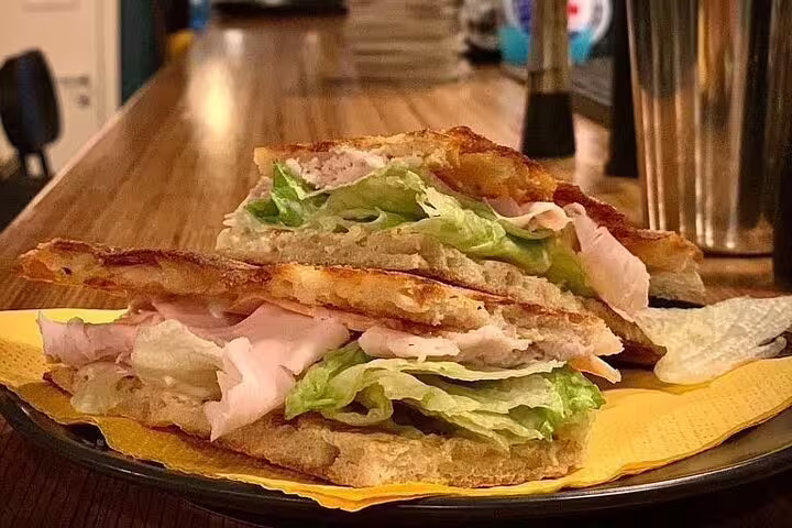 Delicious Italian sandwich with fresh lettuce and turkey on a rustic wooden table, part of the Vatican Craft Beer Foodie Tour.