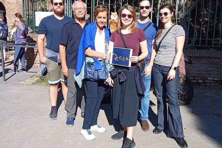 Group of tourists smiling outside the Domus Aurea entrance, holding a C.I.S. Tours sign, ready for a Rome virtual reality experience.