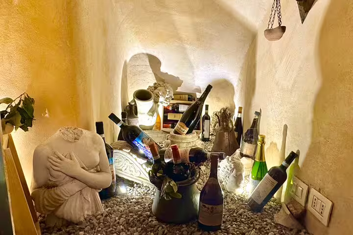 Cozy Roman alcove filled with assorted wine bottles and sculptures, showcasing atmospheric cellar for Fabullus menu pairing