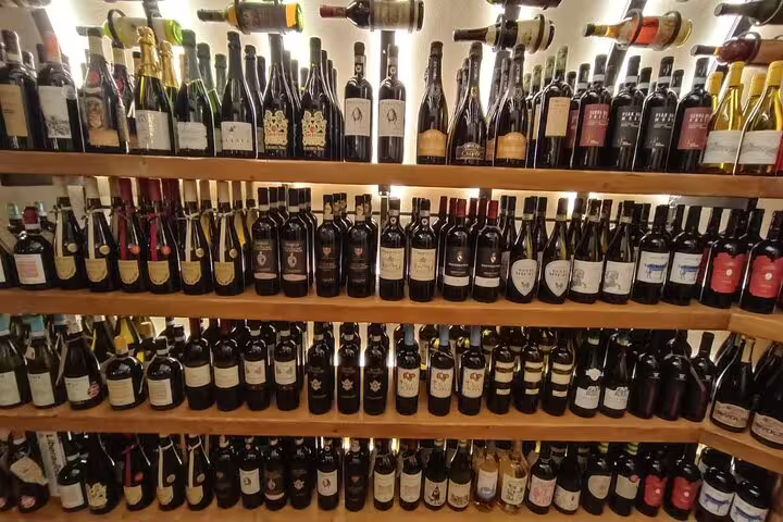 Wall of Italian wine bottles in a Rome enoteca showcasing labels for the Fabullus menu and expert wine pairing tour