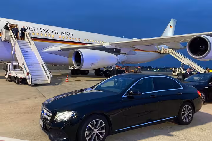 Chauffeured car beside a large airplane at Fiumicino Airport for seamless private transfers from Rome.